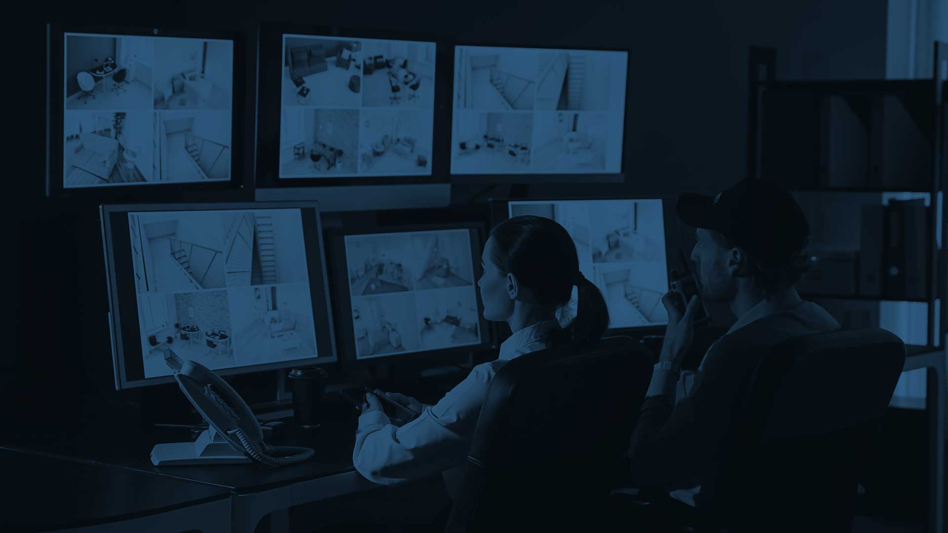 Two security professionals monitoring video surveillance screens